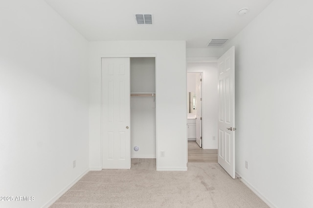 unfurnished bedroom with light colored carpet and a closet