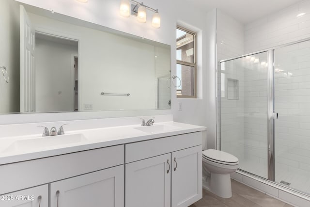 bathroom featuring tile patterned floors, vanity, toilet, and a shower with door