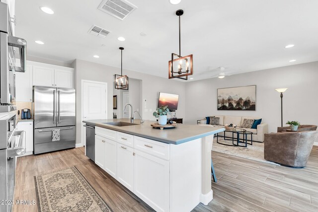 kitchen with a center island with sink, light hardwood / wood-style flooring, appliances with stainless steel finishes, sink, and white cabinetry