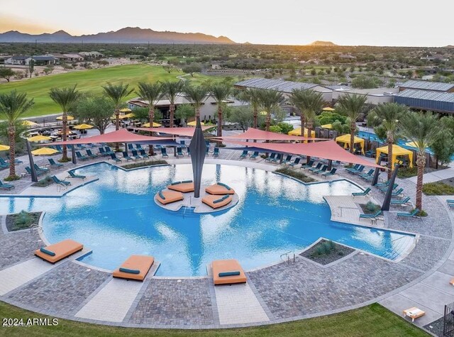 pool at dusk with a mountain view and a patio area