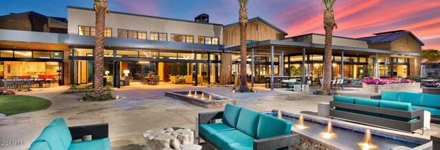 back house at dusk featuring an outdoor living space with a fire pit and a patio area