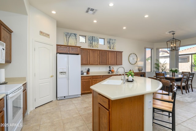 kitchen featuring pendant lighting, sink, white appliances, a kitchen island with sink, and light tile patterned floors