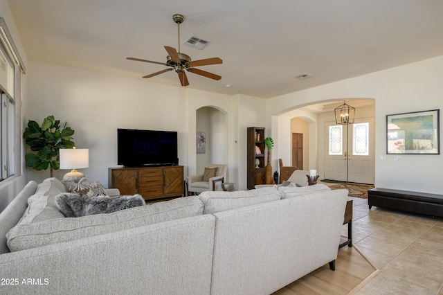 tiled living room with ceiling fan with notable chandelier