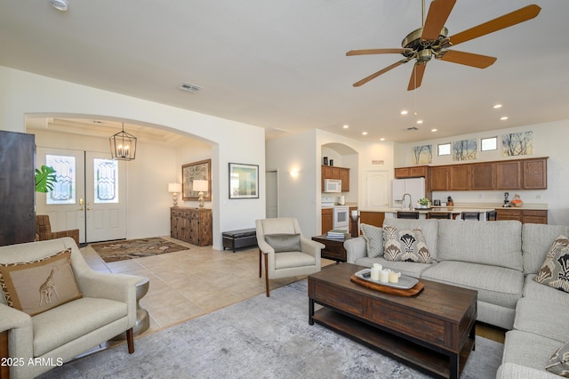 living room featuring light tile patterned floors, sink, and ceiling fan with notable chandelier