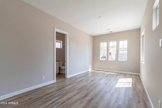 unfurnished bedroom with wood-type flooring and ensuite bath