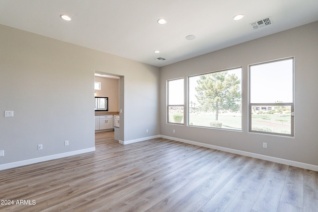 unfurnished living room featuring a wealth of natural light and light hardwood / wood-style floors