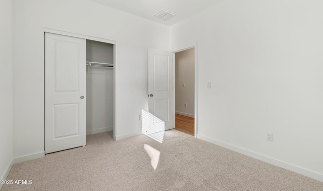 unfurnished bedroom featuring light colored carpet and a closet