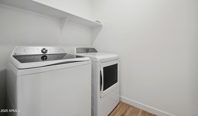 washroom with washing machine and dryer and light hardwood / wood-style flooring