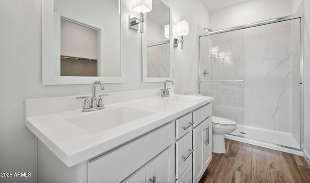 bathroom featuring a shower with door, vanity, hardwood / wood-style floors, and toilet