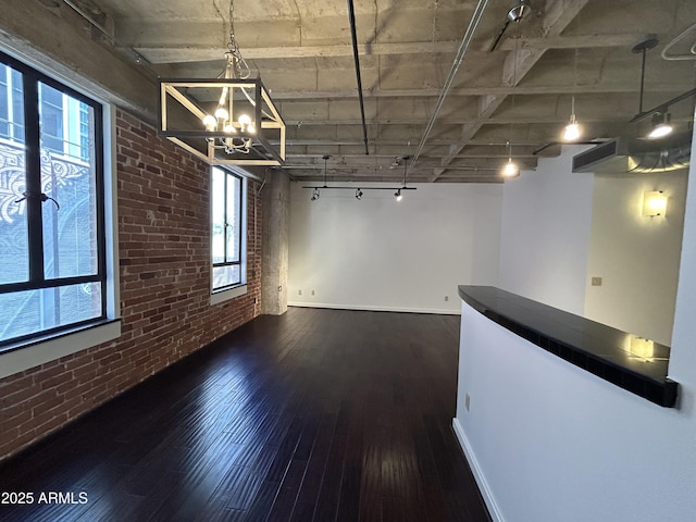 114 W Adams St Unit 302, Phoenix, AZ 85003 - unfurnished dining area with brick wall, track lighting, wood-type flooring, a chandelier, and baseboards