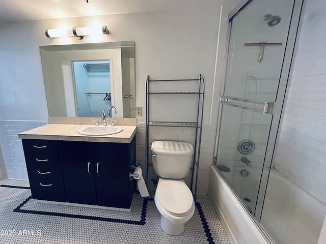 114 W Adams St Unit 302, Phoenix, AZ 85003 - full bathroom featuring toilet, vanity, tile patterned floors, tile walls, and bath / shower combo with glass door
