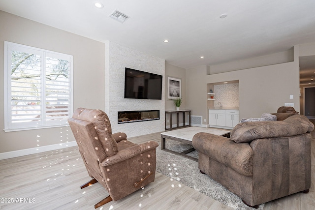 living area with recessed lighting, a fireplace, visible vents, and baseboards