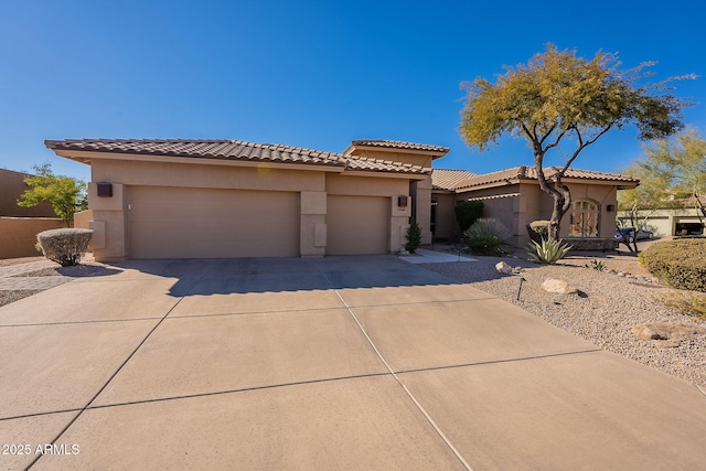 mediterranean / spanish-style house with a tile roof, an attached garage, driveway, and stucco siding