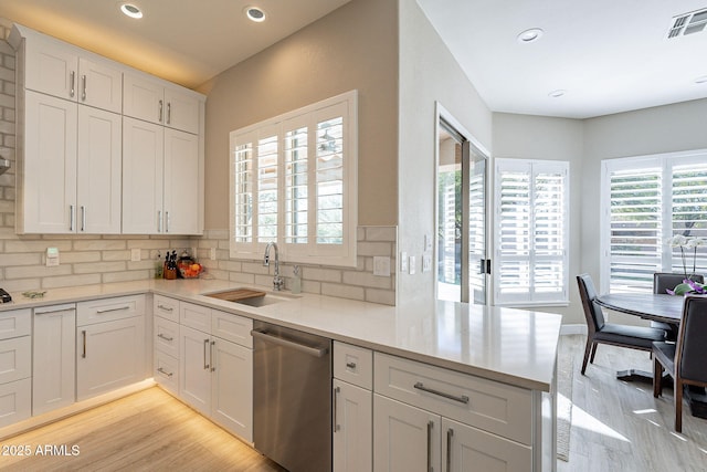 kitchen featuring visible vents, light countertops, decorative backsplash, stainless steel dishwasher, and a sink