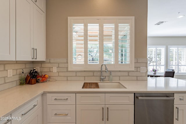 kitchen featuring stainless steel dishwasher, light countertops, white cabinets, and a sink