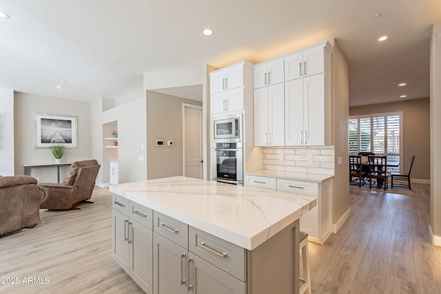 kitchen with stainless steel appliances, open floor plan, a center island, and light wood-style flooring