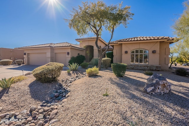 mediterranean / spanish-style home featuring stucco siding, concrete driveway, an attached garage, and a tile roof