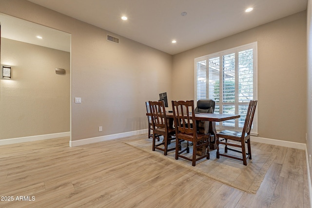 dining room with light wood finished floors, visible vents, and baseboards