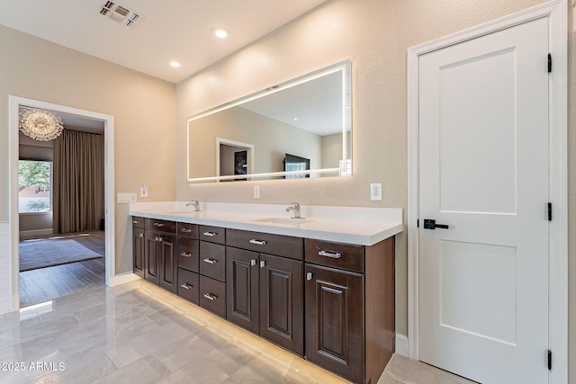 full bath with double vanity, visible vents, baseboards, and a sink