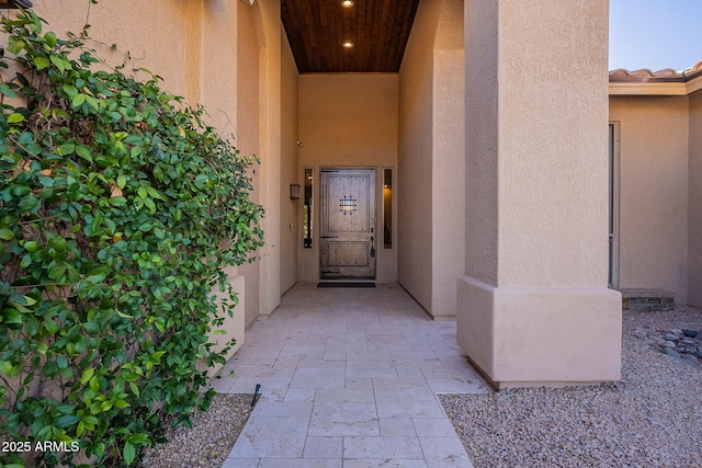 property entrance with a tile roof and stucco siding