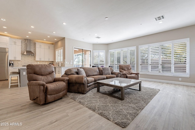 living room featuring visible vents, recessed lighting, baseboards, and light wood-style floors