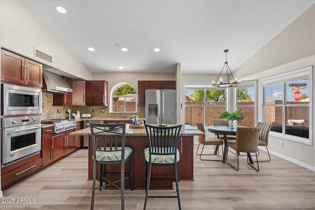 1030 S Brentwood Ct, Chandler, AZ 85286 - kitchen with appliances with stainless steel finishes, wall chimney exhaust hood, vaulted ceiling, decorative backsplash, and a chandelier