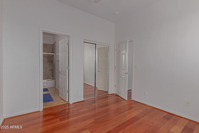 16600 N Thompson Peak Pkwy Unit 1072, Scottsdale, AZ 85260 - unfurnished bedroom featuring baseboards, ensuite bath, wood finished floors, and a closet