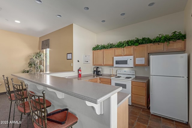 16600 N Thompson Peak Pkwy Unit 1072, Scottsdale, AZ 85260 - kitchen with light countertops, a kitchen bar, light brown cabinetry, a peninsula, and white appliances