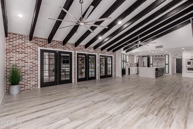 unfurnished living room featuring french doors, beam ceiling, light wood-style floors, brick wall, and visible vents
