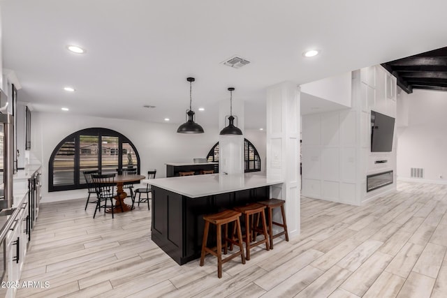 kitchen with white cabinetry, a kitchen bar, recessed lighting, wood finish floors, and visible vents