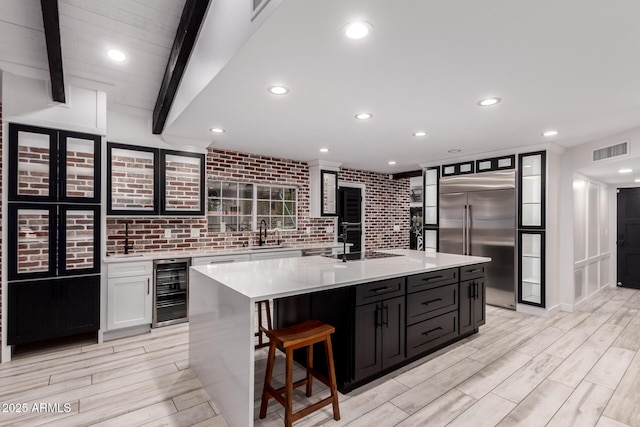 kitchen with white cabinetry, light countertops, built in fridge, beverage cooler, and visible vents