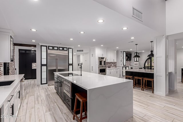 kitchen with built in appliances, visible vents, a spacious island, and backsplash