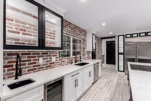 kitchen featuring white cabinets, wine cooler, a sink, and stainless steel appliances