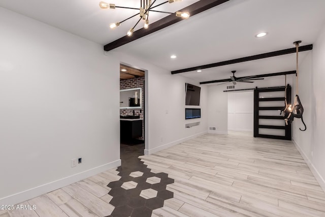 unfurnished room featuring beam ceiling, a barn door, and baseboards