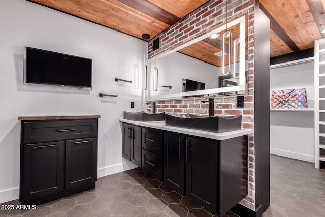 full bath featuring wood ceiling, vanity, tile patterned flooring, brick wall, and baseboards