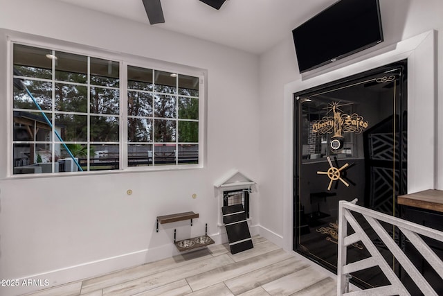 interior space featuring a ceiling fan, baseboards, and wood finished floors