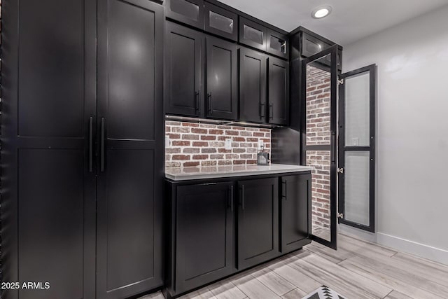 kitchen with glass insert cabinets, light countertops, refrigerator, and dark cabinetry