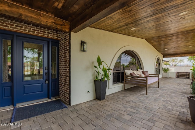 doorway to property featuring stucco siding, a patio, and brick siding