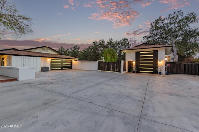 garage featuring driveway, a gate, fence, and central AC