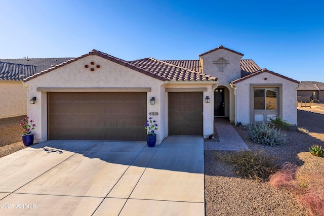 mediterranean / spanish home featuring a garage, concrete driveway, a tile roof, and stucco siding