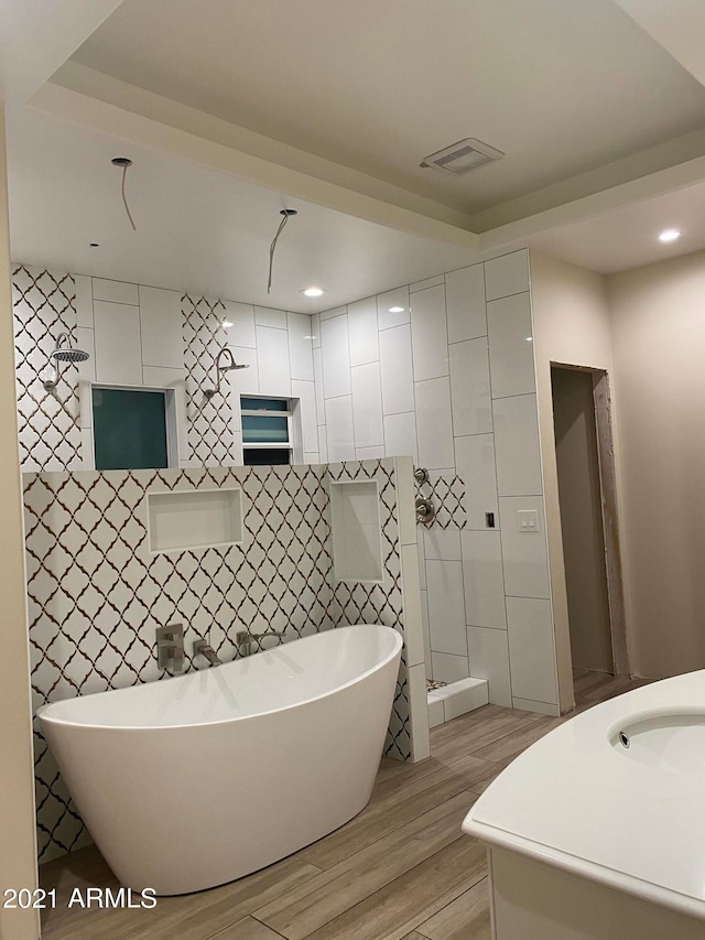 bathroom with tile walls, separate shower and tub, and vanity