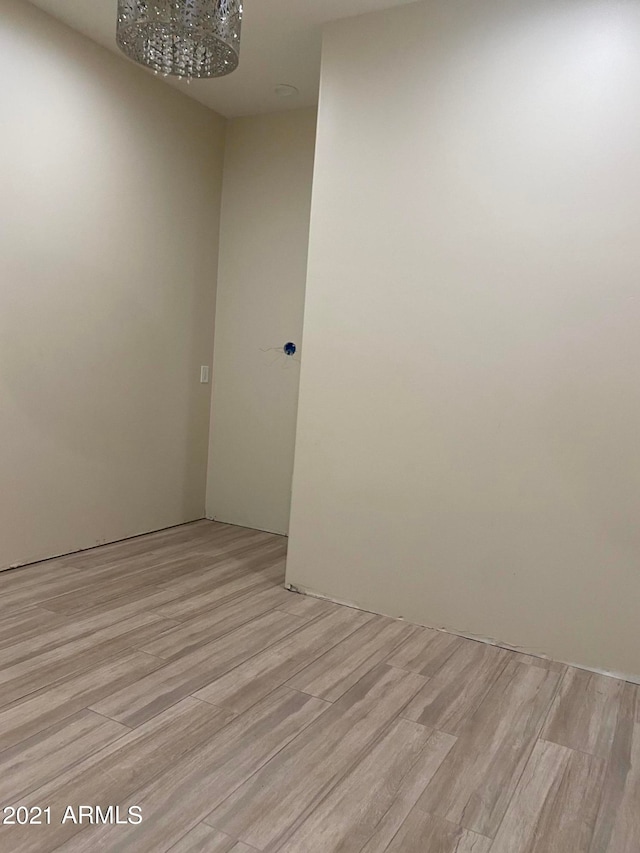 unfurnished room with a chandelier and light wood-type flooring