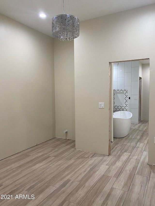 unfurnished room with an inviting chandelier and light wood-type flooring