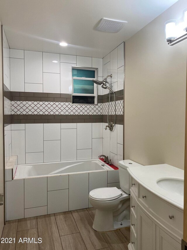 full bathroom with tiled shower / bath combo, vanity, toilet, and hardwood / wood-style floors