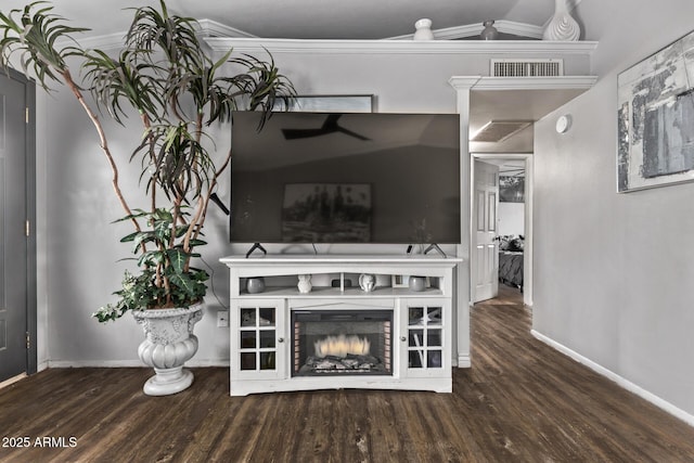 unfurnished living room featuring dark wood-style flooring, visible vents, baseboards, a lit fireplace, and ornamental molding