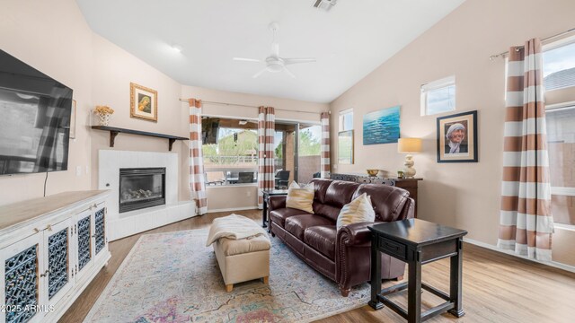 living room with wood finished floors, a ceiling fan, a fireplace, lofted ceiling, and baseboards