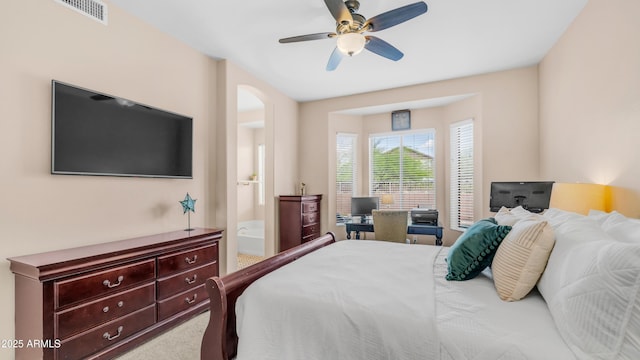 bedroom featuring carpet, a ceiling fan, arched walkways, and a desk