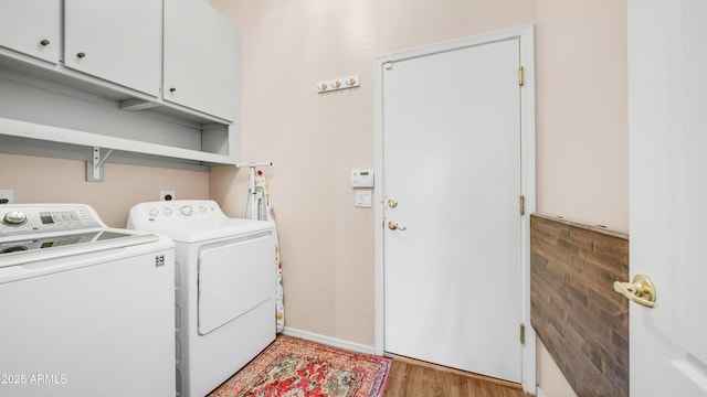 laundry area with cabinet space, independent washer and dryer, light wood-style flooring, and baseboards