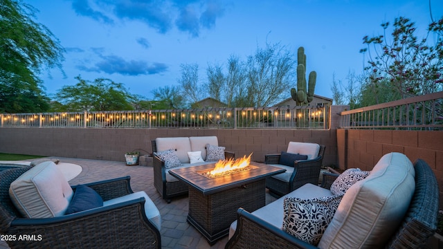 patio terrace at dusk with an outdoor living space with a fire pit and a fenced backyard