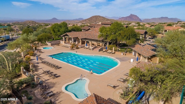 community pool featuring a hot tub, a pergola, a patio area, a mountain view, and fence